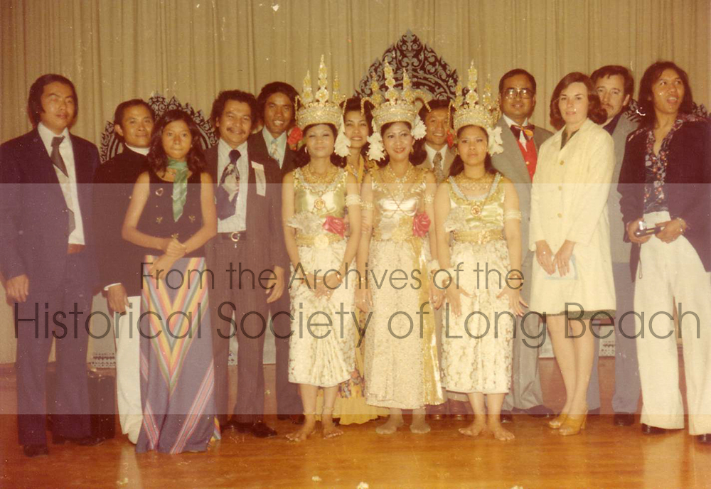 This photo was taken in April 1976 at Long Beach Wilson High School during the Cambodian New Year celebration. It shows the sponsors and performers of the first New Year event after the arrival of evacuees and refugees in the area. Leng Hang, a renowned Cambodian dancer, is seen in the center. She later focused on teaching traditional dance to younger generations and stopped performing publicly.