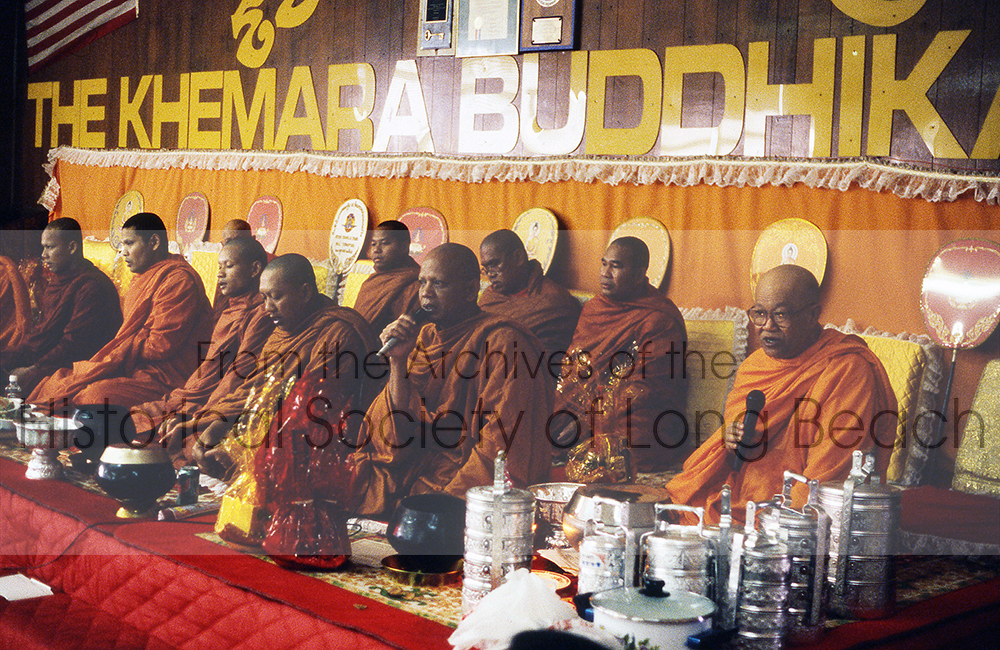 Venerable Dr. Kong Chhean (far right) at the Wat Khemara Buddhikaram (Khmer Buddhist Temple) with other monks during a ceremony. The aluminum containers hold food brought by attendees to be blessed. At the end of the ceremony, families will enjoy the food picnic-style in the main hall.