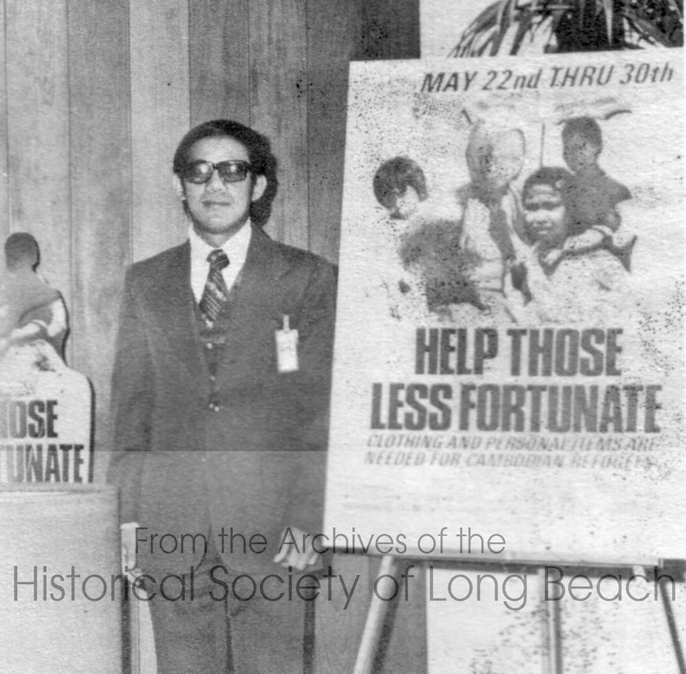 Viradet David Kreng, an engineer at Bechtel, stands by a donation poster appealing for donations of clothing and other personal items for Cambodian evacuees at Camp Pendleton in San Onofre, California. This photo was featured in Bechtel News Southern California in June 1975. (David Kreng Collection)