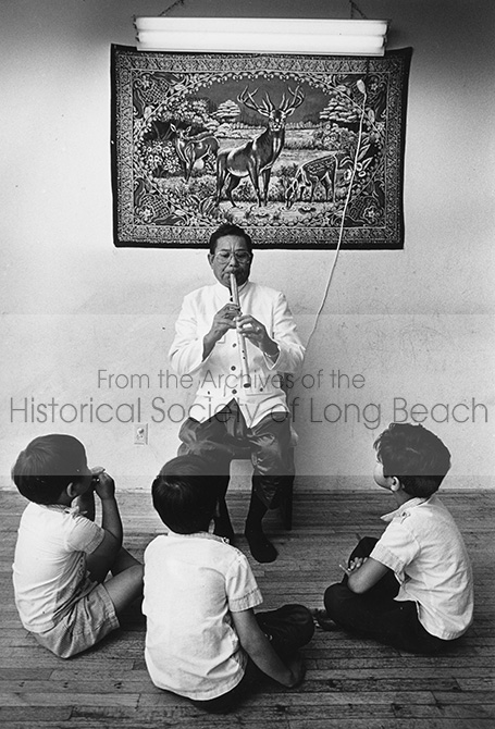 Pon Yinn plays the flute for his three young sons in his Long Beach apartment. (Photo taken by Long BeachPress-Telegram photographer Bruce Chambers on June 29, 1988.)