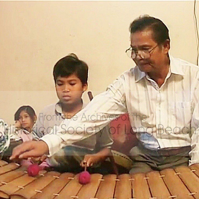 Pon Yinn teaching his son, Andrew, the roneat ek, a Cambodian xylophone.
