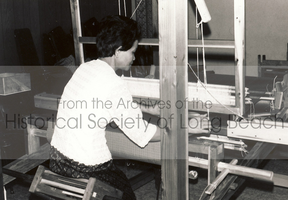 In the 1980s and 1990s, the Arts of Aspara, a cultural center founded by the United Cambodian Community, Inc. in Long Beach, sought to recreate and maintain the art of weaving. In this photo, a local Cambodian woman illustrates how to use the wooden loom.