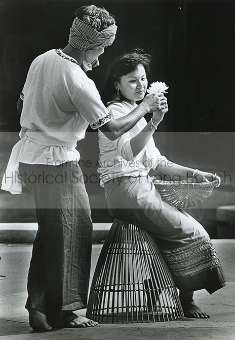 Two Long Beach high school students, Vong York (left) and Ra Chim portray a young couple engaging in playful flirtation in the final scene depicted in the popular folk dance Robam Nesat or “The Fishing Dance.” Ra Chim sits on the Ang Rut, the bell-shaped fishing trap used to catch larger fish in shallow waters used by the young men in the dance and holds the Chhneang, the braided bamboo baskets that act as strainers, that young women use in the dance. The scene depicts the couple’s courtship and falling in love. (The Long Beach Press-Telegram, October 5, 1985. Photographer: Bruce Chambers)