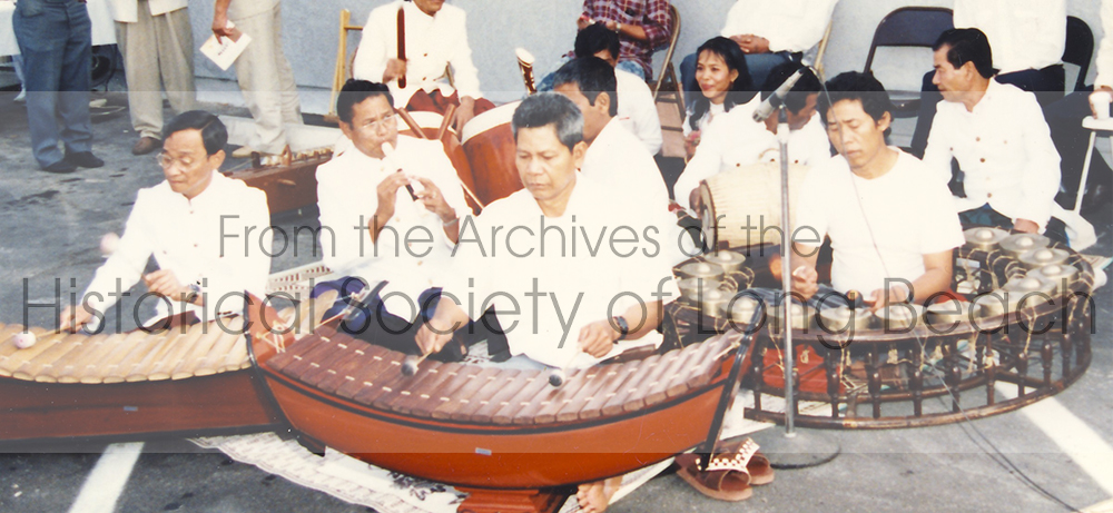 Image of musicians playing in the Pin Peat ensemble with Master musician Yinn Pon (second row, left) plays the flute at a community event.