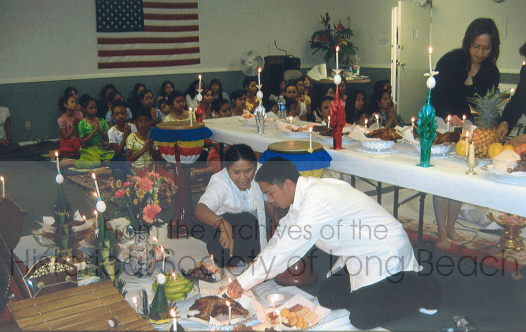 Parents and supporters of the Spirit of Khmer Dance Troupe help set up the altar or the Sompeah Kruu ceremony held at the offices of the Cambodian Association of America in Long Beach, Thursday, November 2006. In addition to items used by dancers and musicians, they have prepared food offerings which include cooked meat and fresh fruit. Also included at ceremonial objects, known as baaysei.