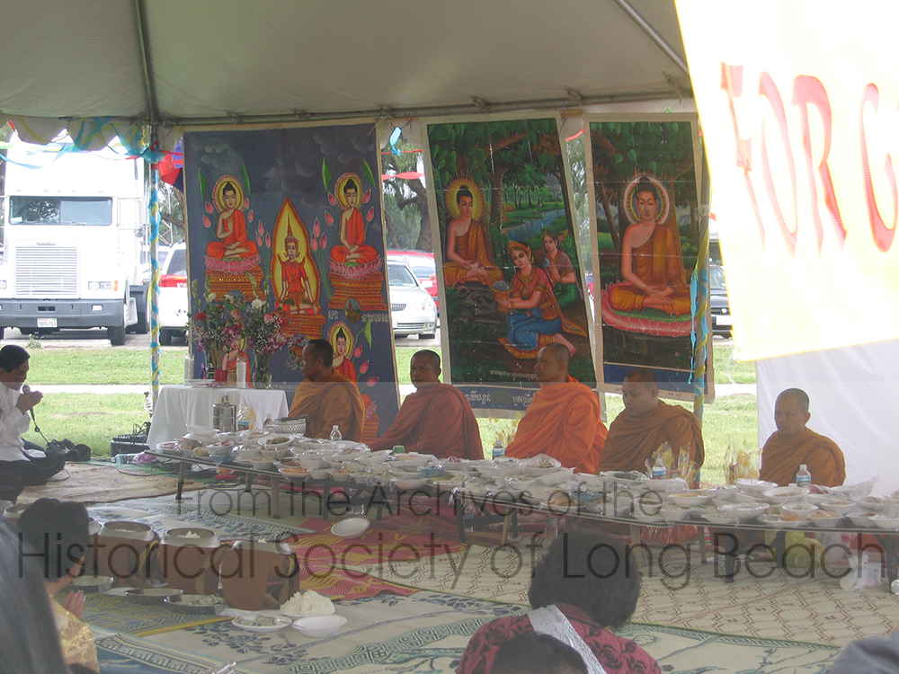New Year celebration in Long Beach, CA. A large tent has been set up for monks who have gathered from different area temples. The table is set with food offerings brought by attendees. The monks bless the food which brings merit to those who brought it and their ancestors.