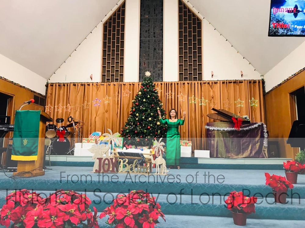 In addition to being a medical doctor, Christina Lee also has a degree in Divinity and is the Pastor at the Long Beach Cambodian American United Methodist Church. This photo was taken during Christmas, 1021. Dr. Lee also plays the piano to the right, which she learned to play by ear. She is wearing green to symbolize life.