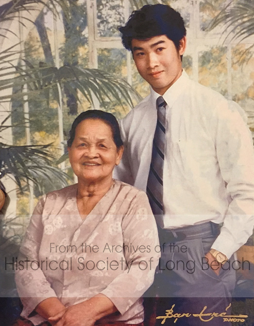 Clark Tang with his grandmother, You Long, about the time of his graduation from high school in Westminster, CA c. 1986. He was about 19 years old. His grandmother arranged to have this photo taken in a studio so he would remember her. Clark says his grandmother was “the queen of my life.” She passed away at the age of 83.