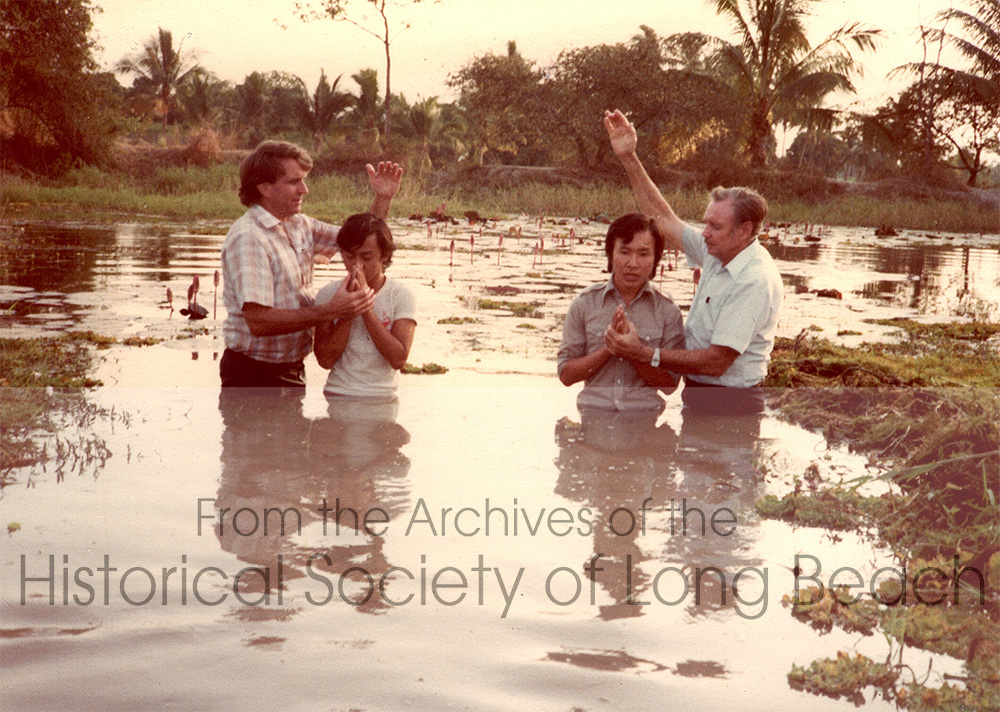 Dan Durke (2nd from left in white t-shirt) at Khao-I-Dang refugee camp in Thailand, 1981. Dan is being baptized by a 7th Day Adventist missionary. Dan wanted to learn English and the Church had English classes, but only for those who converted to the faith. Dan understood he could join the classes if he was baptized, but did not fully understand what that meant. He was able to attend English classes, but did not continue with the church when he left Khao-I-Dang.
