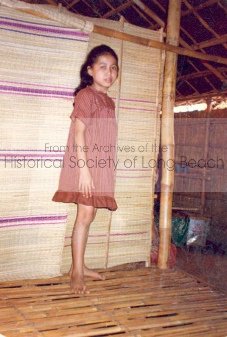 Janet Vanniroth in the orphanage center where her mother worked in the Khao-I-Dang refugee camp, 1980. Woven mats were used to divide the space into rooms for the children. Staff, like Janet’s mother, lived in the office areas, while their children slept in the orphanage center with the other children. The staff prepared meals and dining was communal. When Janet’s mother learned that her husband had escaped to the U.S., she had the photo taken to send to him.