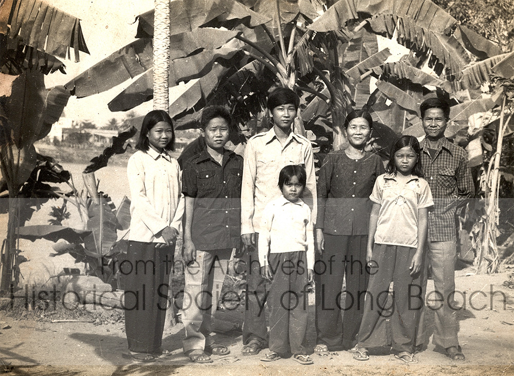 Kam Lou Lopez with family in their village southeast of Phnom Penh, near the Mekong River, Cambodia 1980. From left to right: Kam’s older sister, Amanda; older brother, William; younger sister, Meicy Lou; mother, Fang Phar; Kam; and her father, Man Lou. After the Khmer Rouge period ended in 1979, the family went back to their village where her father tried to start his watch business again, but he was warned to leave. Her father suspected the family might be separated during the journey to the border, so he had this photo taken of them together.