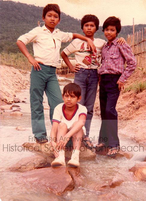 Monorom Neth with his friends from Khao-I-Dang refugee camp in Thailand 1979. Standing, from left, unnamed person, Ratana Nhem, and unnamed person. Monorom Neth is sitting in front of them.