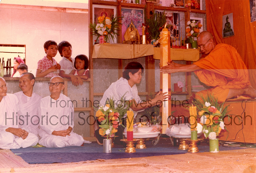 Monorom Neth’s mother, Om Van, offering candles to a monk at a makeshift temple at Chonburi refugee camp, Thailand 1981. Other people in the photo are unidentified.