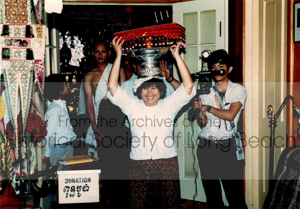 Monorom Neth’s mother, Om Van, is the last to carry Monorom’s robes into the temple sanctuary in Lakewood, CA 1985. In Cambodia, it was customary for every young Cambodian male to shave their head and spend some time as a novice monk. The merit the young man earns by becoming a monk was transferred to his parents, especially his mother. The ordination of a son is a prized gift for a mother and it is clear how happy Monorom’s mother is.