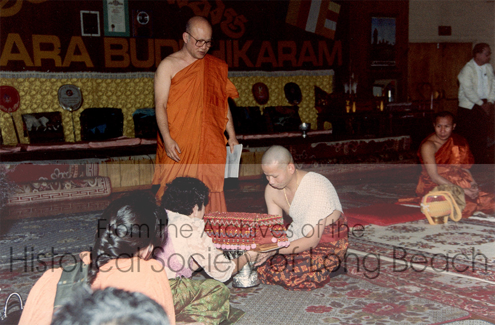 Monorom Neth’s brother, Sarkarl, becoming a novice monk at the Khemara Buddihikaram Cambodian Buddhist Temple in Long Beach, CA, 1988. Monorom’s mother, Om Van, is presenting Sarkarl’s robes to him. The robes are protected by an embroidered and beaded covering called a “trai.” He was ordained by Rev. Kong Cheang, the temple’s Abbot and the first Cambodian Buddhist monk in the U.S.