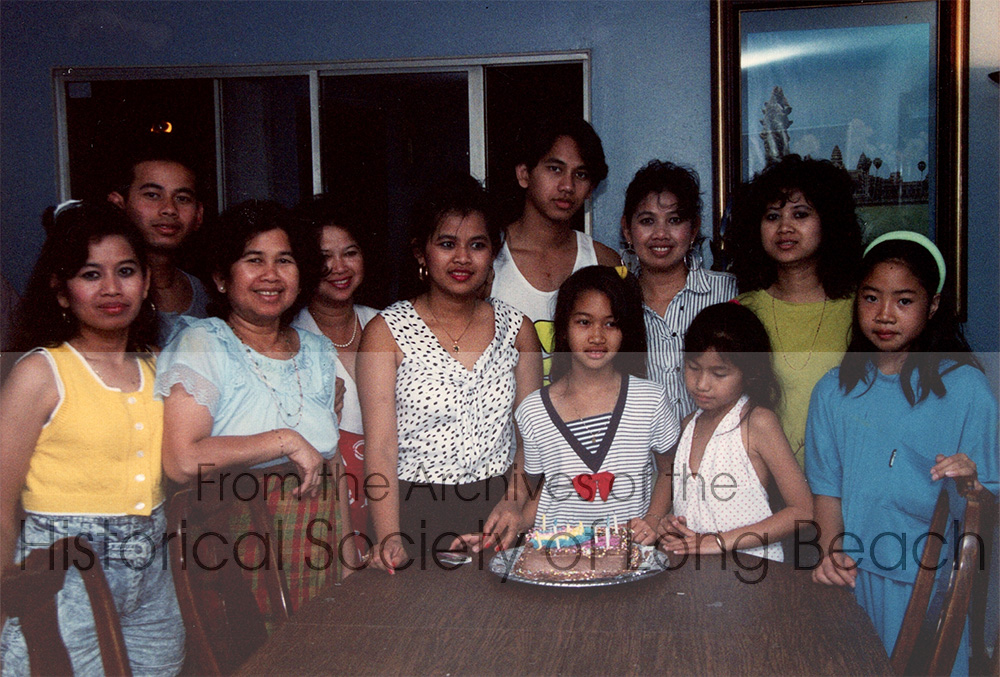 Monorom Neth with family as they celebrate Valerie’s birthday (in front of the birthday cake, wearing the blouse with the red bow) in Bellflower, CA 1989. From left to right: Monorom’s sister, Somealea; behind her, is Sakok; Monorom’s mother, Om Van; unnamed aunt behind her; Monorom’s sister, Somealy; Monorom; his cousin, Valerie Sam; his mother’s youngest sister, Savanna Om; Thida Neth, the two children in white and blue are unnamed. Monorom’s mother, Om Van, adopted Thida after her twin sister died. In Cambodia, it is common for extended family to adopt others from the extended family even when the parents of the adoptee are alive and live nearby.