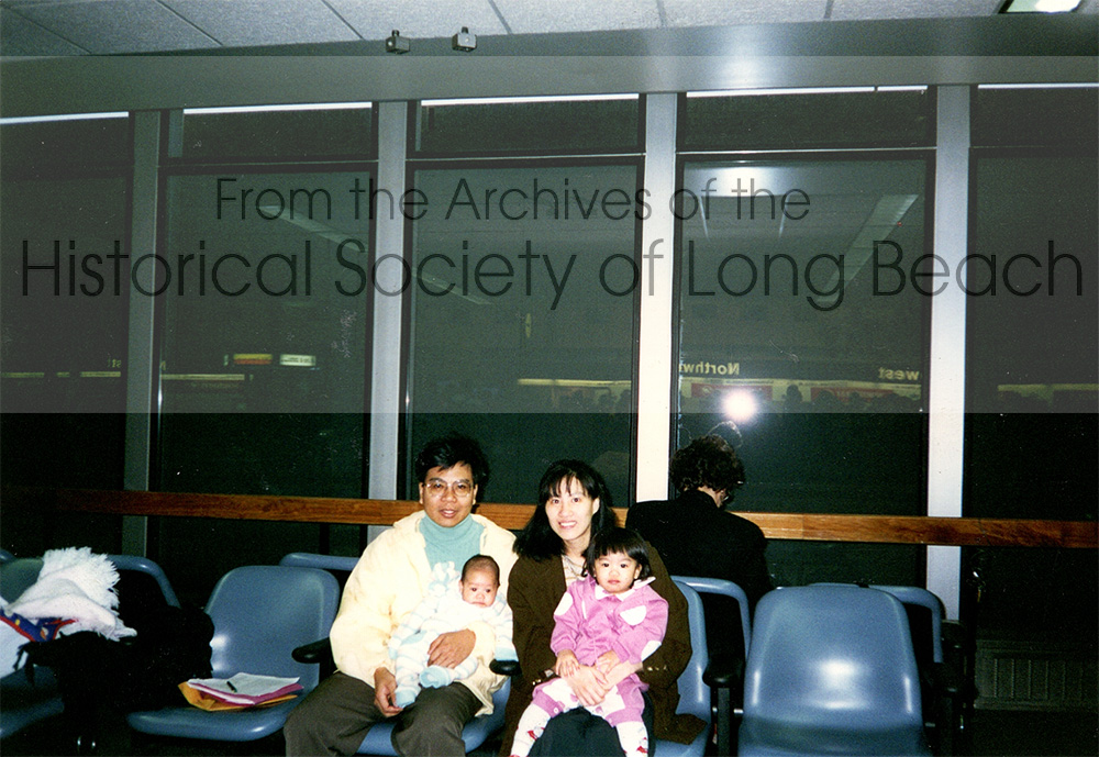 Namoch Sokhom with his family at the St. Paul, MN airport, 1995. Pictured are Namoch and his wife, Shufen Sokhom. Namoch is holding their newborn son, Lekhana and Sufen is holding their daughter, Rattnak. They are waiting to board a plane to visit Cambodia.