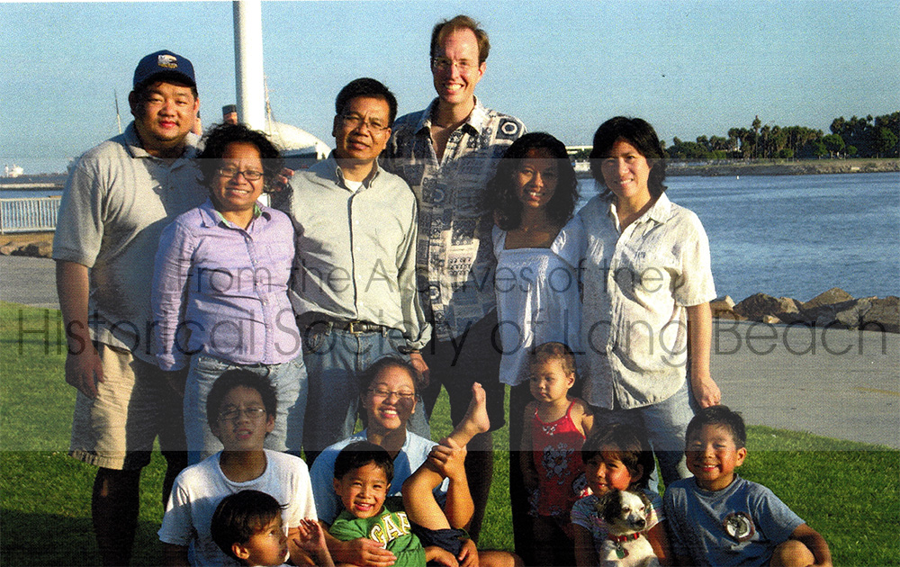 Namoch’s family gathered for a picnic in Long Beach, CA 2008. Back row, from left,: Sovathana Sokhom’s husband, Kim Hong San; Namoch’s younger sister, Sovathana Sokhom; Namoch Sokhom; Sophois Sokhom’s husband, Conor Weir; Namoch’s youngest sister, Sophois Sokhom; and Namoch’s wife, Shufen Sokhom. In the middle row seated are Namoch’s children, Lekhana Sokhom and Rattnak Sokhom (both wearing glasses); they are holding two of Sophois’ children, Sorika and Satya Weir. Standing in the red shirt is Sovathana’s son, Indra Sokhom-San. Seated with the dog (Pinky) is Sophois’ daughter Devy Weir; next to her in the blue shirt is Sovathana’s oldest son, Chakra Sokhom-San.