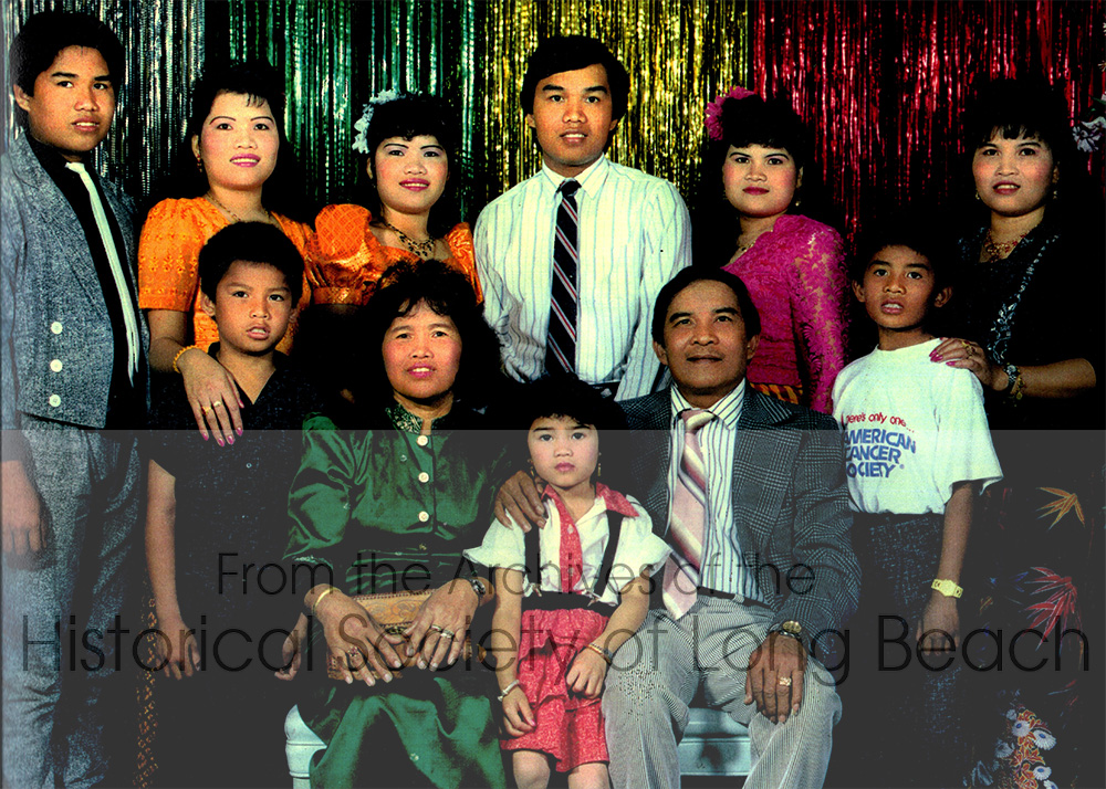Rom Hoy with her family in Long Beach, CA 1987. Back row from left to right: her brother, Tony Hoy; Rom; her twin sister, Roeun Hoy; brother, Young Hoy; sister, Ran Hoy; brother, David Hoy; sister, Ren Hoy. Front row from left to right: brother, Yim Hoy; her mother, Lach Yiv; sister, Cindy Hoy; and her father, Hoeun Hoy. Photo taken in Long Beach, CA 1987.