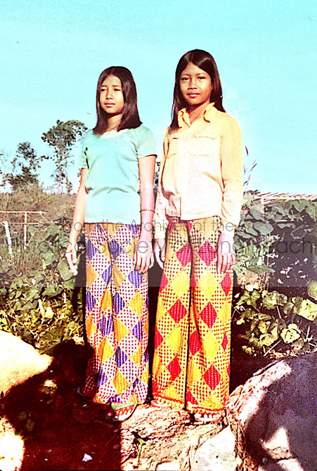 Sithy Yi (right) with her sister, Sithea in a garden at the Kampot Refugee Center, Thailand, 1981. They were maybe 13 and 12 years old. The pants they are wearing were probably made from sarongs.