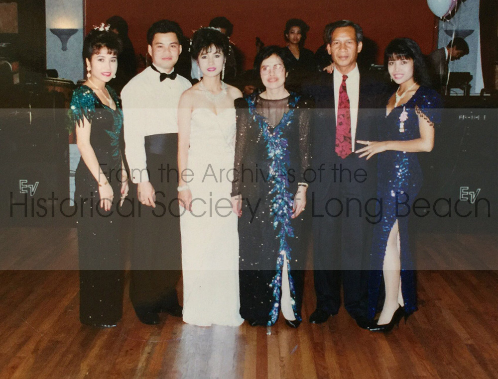 Sithy Yi (far right) at her sister, Sithea Yi’s wedding to Richer San at the Apsara restaurant in Long Beach, CA 1991. From left to right: Sithea’s sister, Jennier Diep (Sitheavy Yi); the groom, Richer San; the bride, Sithea (Yi) San; her mother, San Thi Tran; her father, Len Diep; and Sithy Yi. In the background are the band and singer.